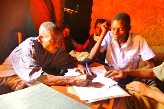 Alinoji Muzairoi and Amisi Monongo signing the mediation sheet at Kigongo