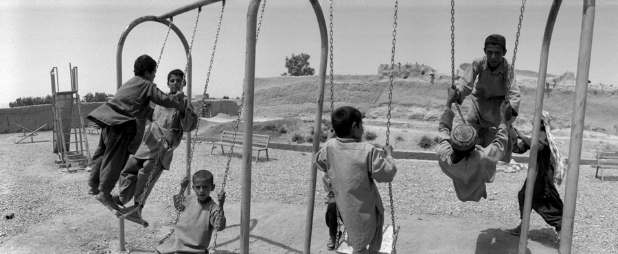 Afghan boys play on swings in Dand District South of Kandahar City, Afghanistan. In 2009, this district teetered on the verge of collapse as insurgents operated freely, intimidating and terrorizing the local population and government officials. Although it is not completely secure, a long term counterinsurgency (COIN) operation implemented by Canadians turned the area around. © Louie Palu/ZUMA Press/Alexia Foundation