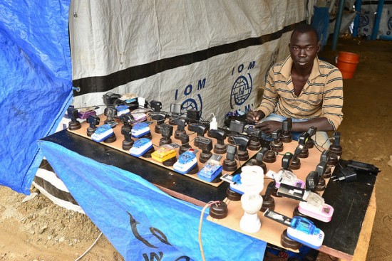 A young man charges phones at a UN IDP camp in South Sudan. Image credit: https://flic.kr/p/ndpFQb by Tom McShane 